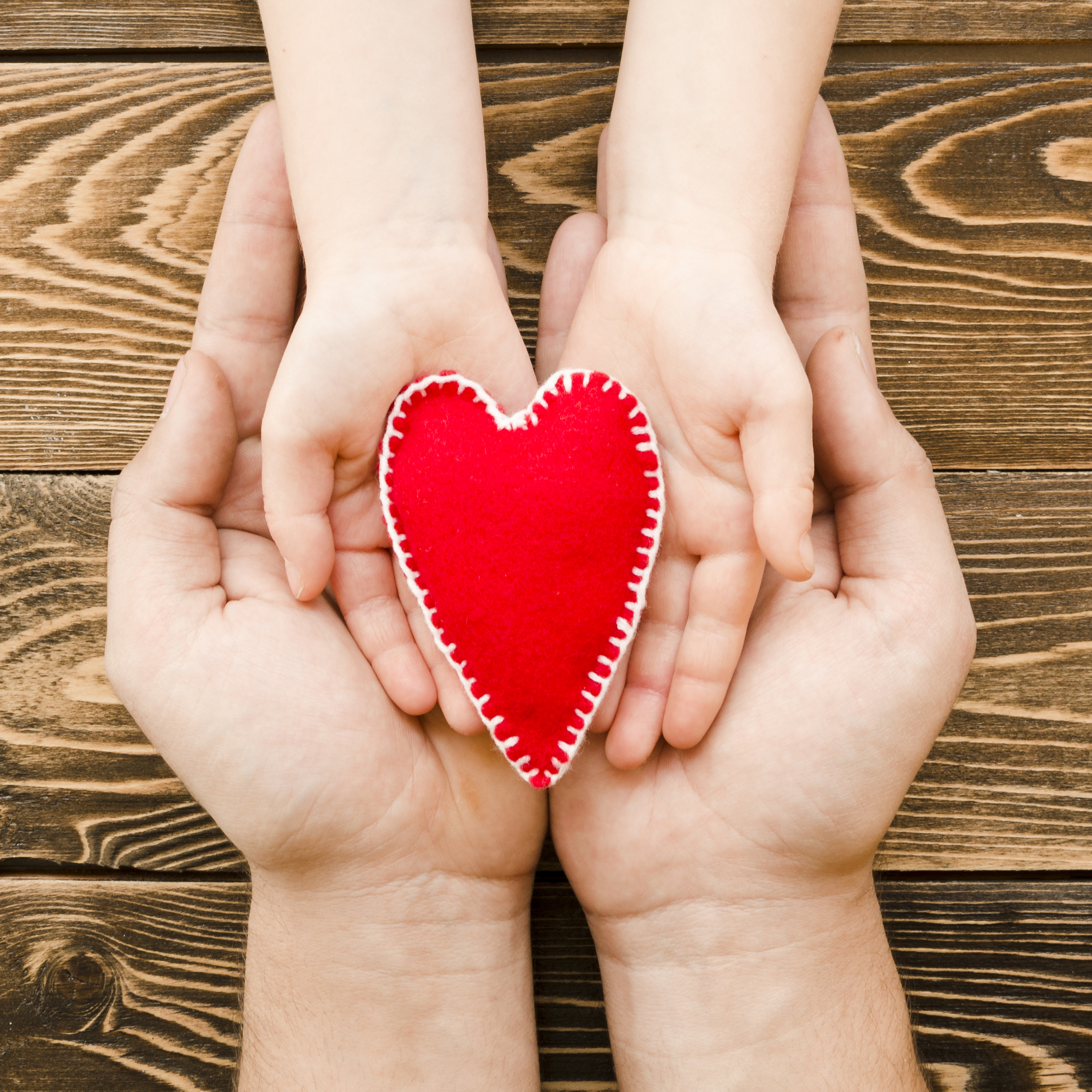 people-holding-red-heart-hands-wooden-background